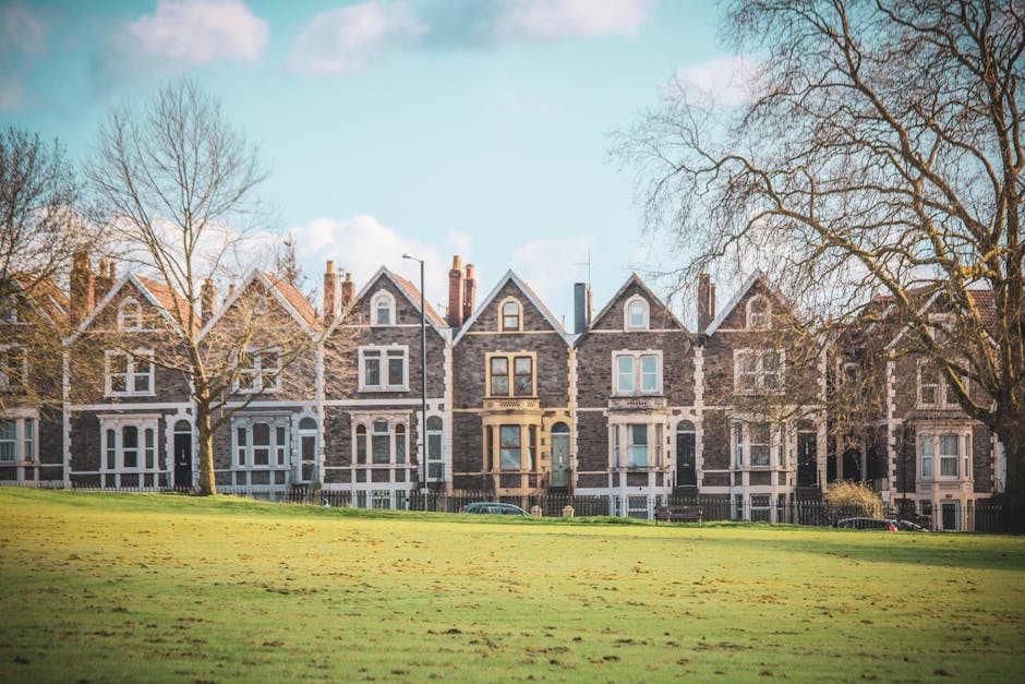 Photograph of a row of Victorian terrace residential buildings on Haverstock Hill NW3, showcasing a variety of brightly painted facades including blue, green, and beige. The buildings feature large sa